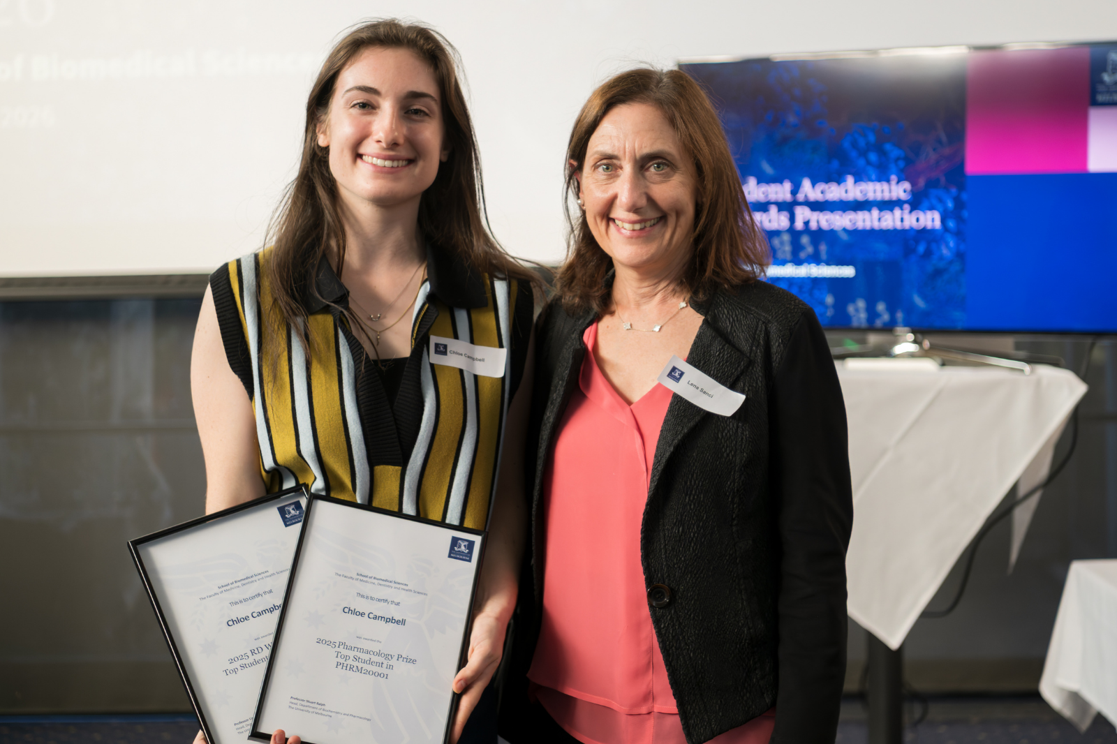 two women pose for photo holding certificates