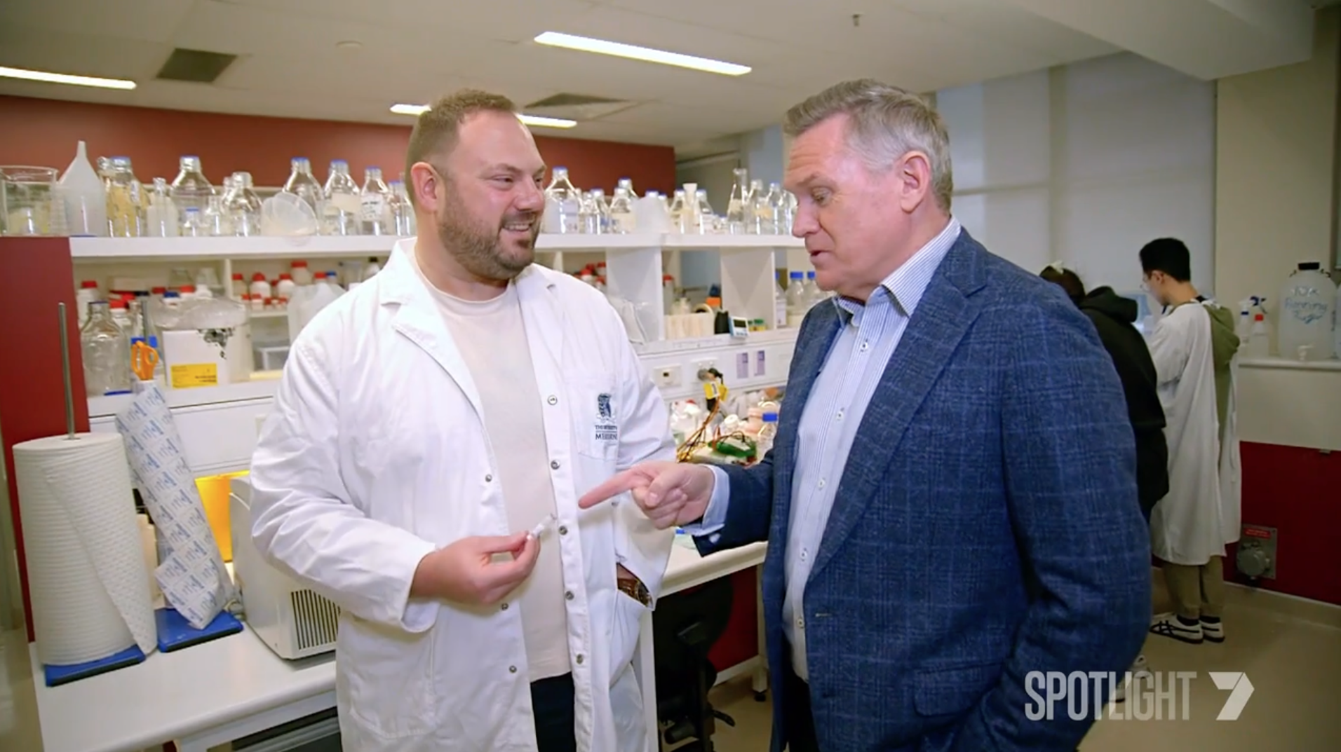 Two men talking in scientific laboratory setting