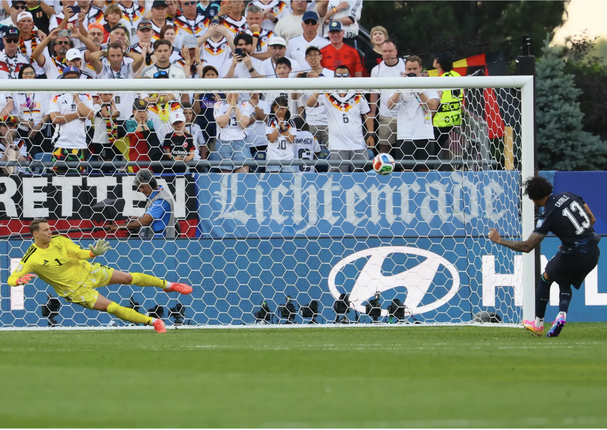 two soccer players, one is kicking goal