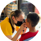 Woman wearing surgical mask does eye test on child