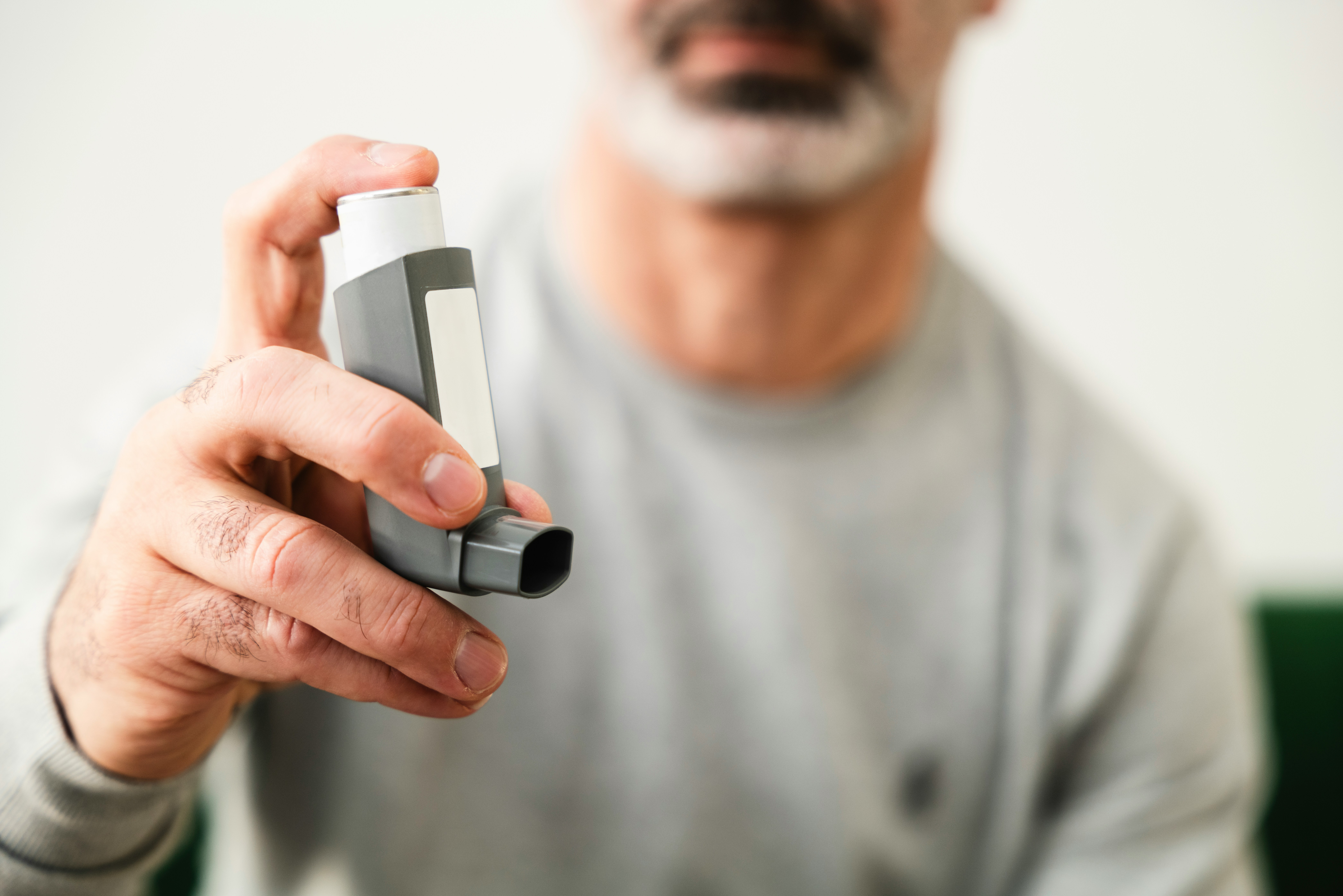Man holds inhaler for asthma medication