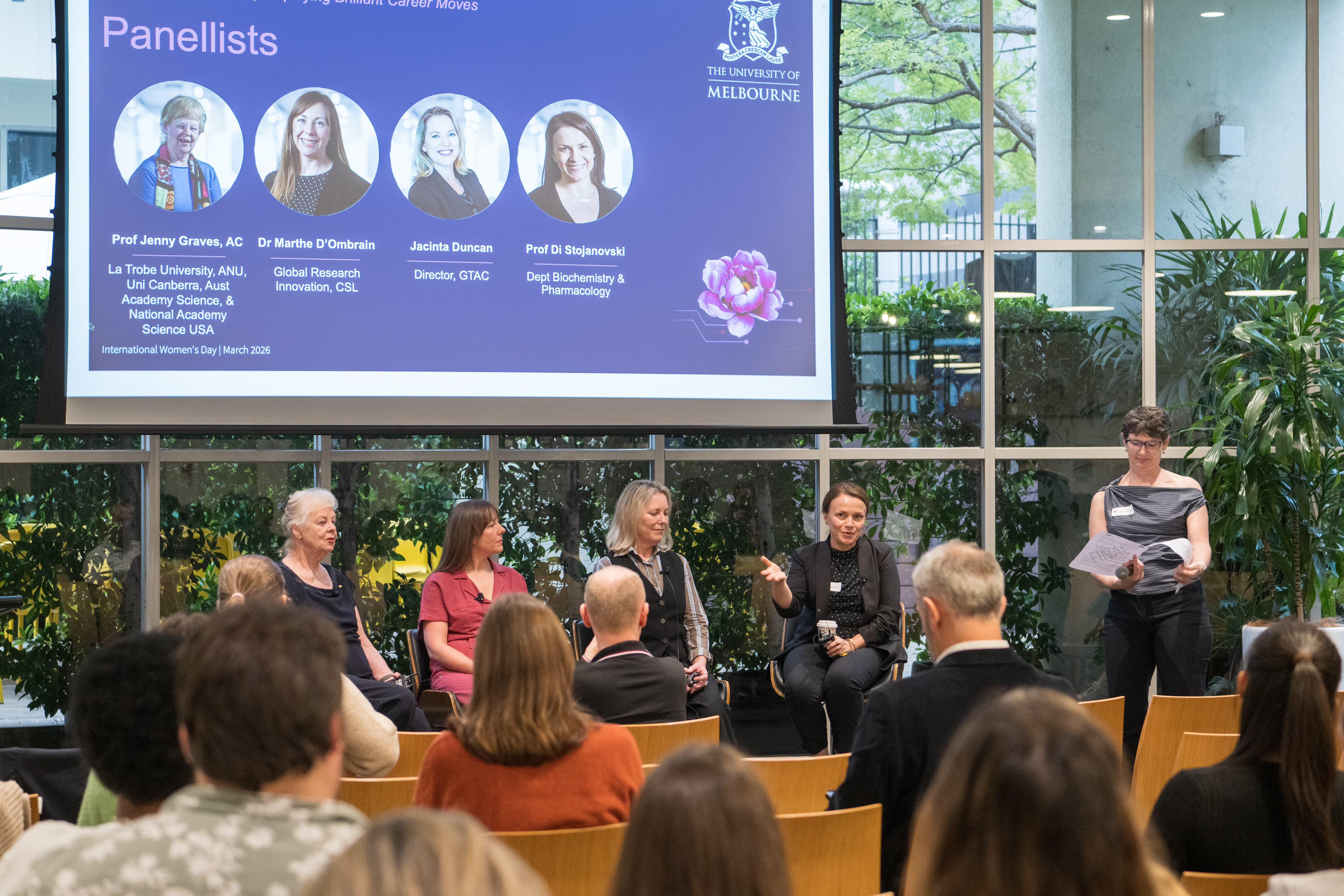 Panel of women speakers with AV screen behind them at an event