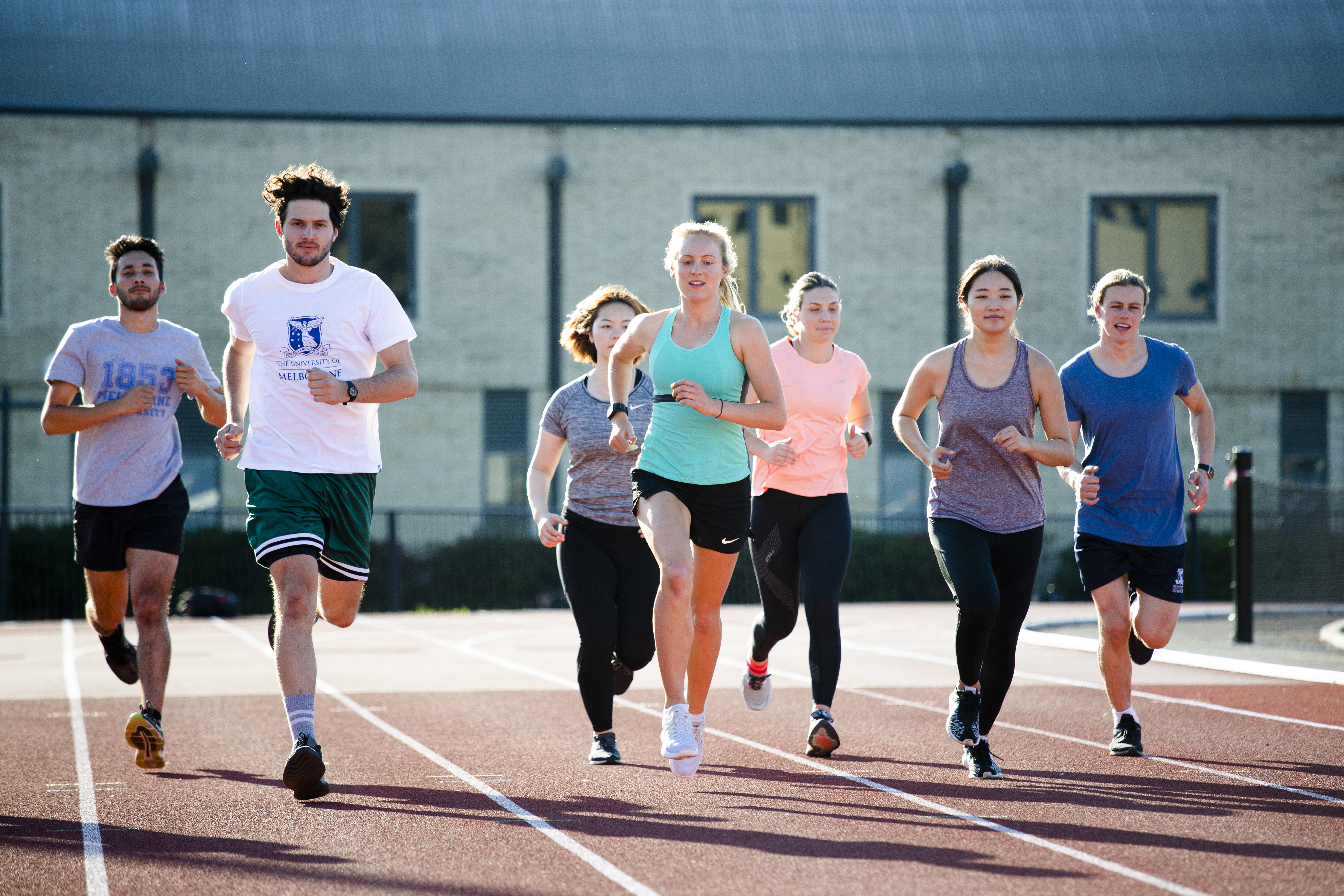 A group of students running together on an athletics track